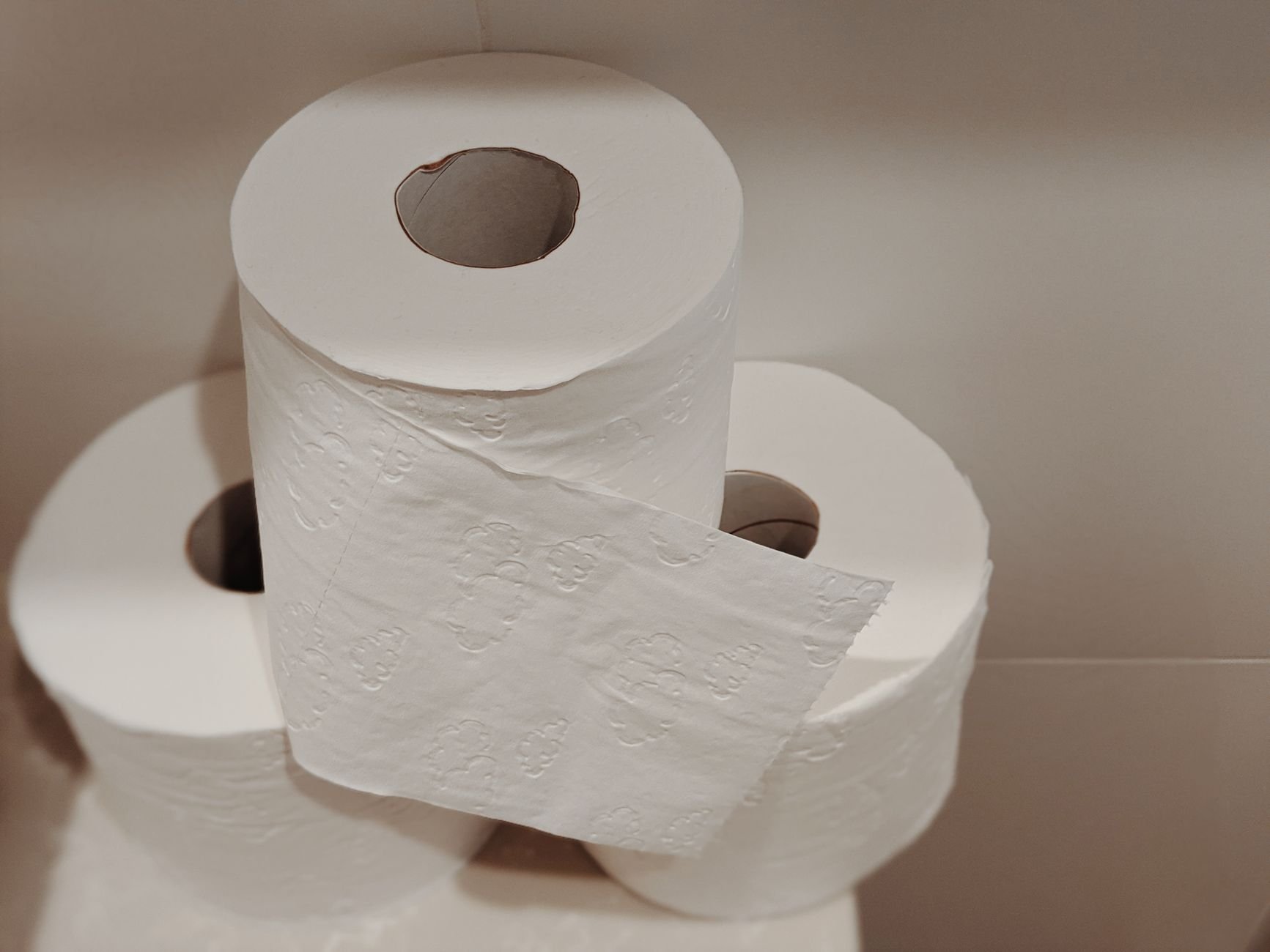 A neatly stacked pile of white toilet paper rolls on a clean ground